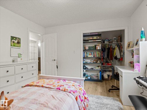 Bedroom featuring light wood-finish flooring, a white trim door, and a built-in closet with shelving and hanging space - 4 Lovatt Place, St. Albert, AB - Indoor Photo Showing Bedroom