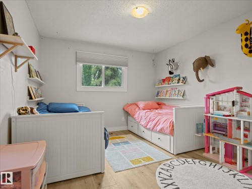 Bright room featuring wood-finish flooring, a flush-mount ceiling light, and a window with a roller shade - 4 Lovatt Place, St. Albert, AB - Indoor Photo Showing Bedroom