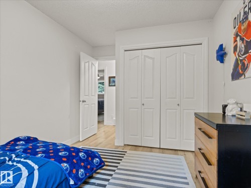 Bright interior with light wood-finish flooring, white walls, and a white bi-fold closet door - 4 Lovatt Place, St. Albert, AB - Indoor Photo Showing Bedroom