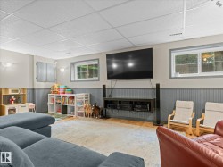 Finished lower level featuring recessed lighting, a drop ceiling, wood-finish flooring, and two windows providing natural light - 