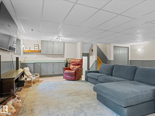Lower level recreation room featuring wood-finish flooring, a drop ceiling, and wall-mounted lighting - 4 Lovatt Place, St. Albert, AB - Indoor Photo Showing Living Room