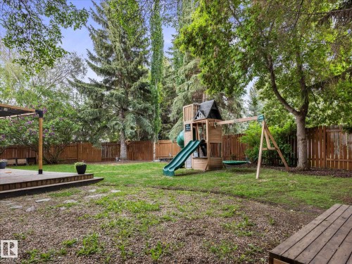 Spacious backyard featuring a wooden deck with pergola, mature trees, and privacy fencing - 4 Lovatt Place, St. Albert, AB - Outdoor With Backyard
