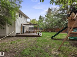 Expansive backyard featuring a multi-level wood deck with a pergola, a sliding glass door entry, and mature perimeter trees - 
