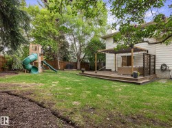 Spacious backyard featuring a large wooden deck with a pergola, a sliding glass door for outdoor access, and a wood chip area - 