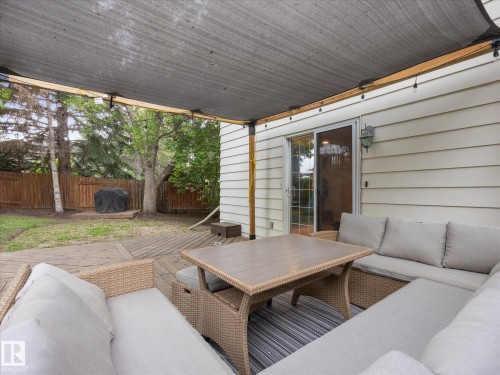 Expansive wood-finish deck with an overhead shade structure, featuring string lighting and direct access to the interior via a sliding glass door - 4 Lovatt Place, St. Albert, AB - Outdoor With Deck Patio Veranda With Exterior