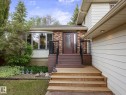 Exterior featuring a red brick facade, cream horizontal siding, a red entry door with decorative glass, a bay window, and a multi-level wood deck and stairs - 4 Lovatt Place, St. Albert, AB  - Outdoor With Exterior 