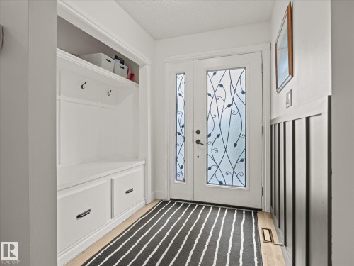 Entryway featuring a double door with decorative glass inserts, built-in mudroom storage with a bench and drawers, upper shelving, and wall hooks - 4 Lovatt Place, St. Albert, AB - Indoor Photo Showing Other Room