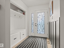 Entryway featuring a double door with decorative glass inserts, built-in mudroom storage with a bench and drawers, upper shelving, and wall hooks - 