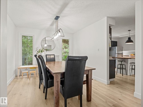 Dining area featuring light wood-finish flooring, white walls, and a modern linear pendant light fixture - 4 Lovatt Place, St. Albert, AB - Indoor Photo Showing Dining Room