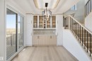Built-in cabinetry with glass-front uppers and wood-finish lowers, geometric tile backsplash, and a contemporary chandelier - 13144 187 Avenue Nw, Edmonton, AB 