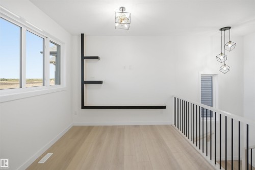 Light wood-finish flooring, built-in shelving, white walls, and contemporary light fixtures - 13144 187 Avenue Nw, Edmonton, AB 