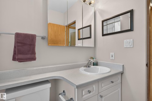 White vanity with silver-tone hardware, an integrated sink, and a light-toned countertop - 14611 109 Avenue Nw, Edmonton, AB 