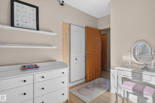 Light wood-finish flooring, white bifold closet doors, and a wood-panel interior door - 14611 109 Avenue Nw, Edmonton, AB 