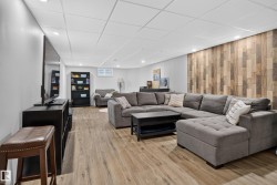 Wood-finish flooring, recessed lighting, drop ceiling, and an accent wall with varying wood tones - 