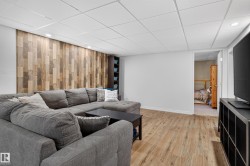 Wood-finish flooring with recessed lighting, a decorative wood plank accent wall, and built-in shelving - 