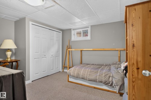 Light-toned carpet flooring, white bi-fold closet doors, a drop-ceiling, and a single window - 14611 109 Avenue Nw, Edmonton, AB 