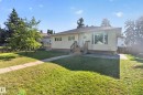 Single-story residence featuring light-colored siding, a prominent bay window, and an inviting front porch with wooden steps - 14611 109 Avenue Nw, Edmonton, AB 