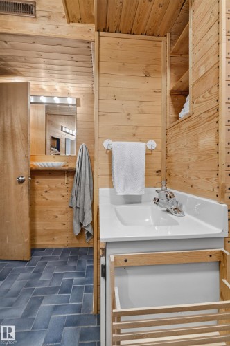 Wood-paneled interior with built-in shelving, a white vanity with integrated sink, and herringbone pattern floor tiling - 14611 109 Avenue Nw, Edmonton, AB 