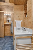 Wood-paneled interior with built-in shelving, a white vanity with integrated sink, and herringbone pattern floor tiling - 