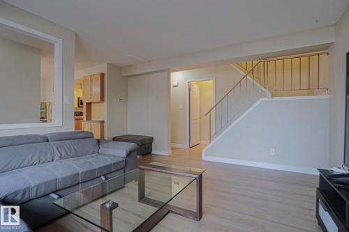 Wood-finish flooring throughout, light-toned walls, and a staircase with metal railings - 319 Telford Court, Leduc, AB 