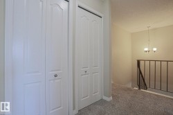White bi-fold closet doors, textured carpet flooring, and a wrought iron stair railing - 