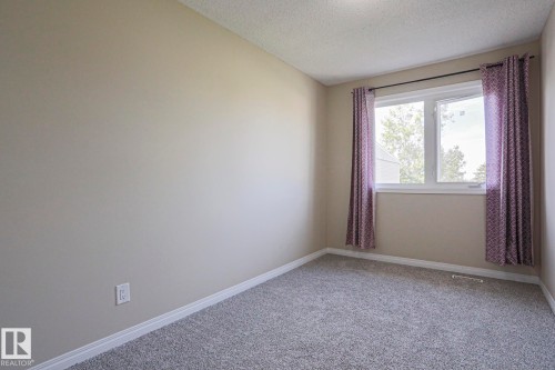 Neutral wall color, carpeted flooring, white trim, window with white frame, and textured ceiling - 319 Telford Court, Leduc, AB 