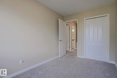 Neutral wall paint, textured ceiling, gray carpet flooring, white trim, and white bi-fold closet doors - 319 Telford Court, Leduc, AB 