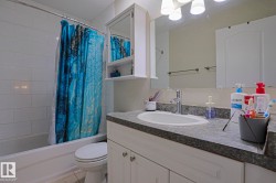 White tile shower surround, integrated bathtub, white vanity with cabinet storage, countertop with integrated sink, and wall-mounted mirror - 