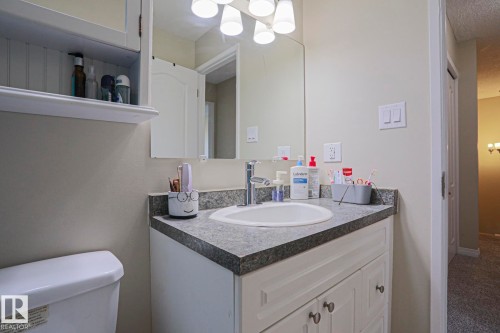 White vanity with cabinet storage, integrated sink, and gray speckled countertop - 319 Telford Court, Leduc, AB 