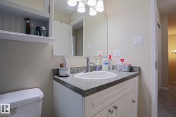 White vanity with cabinet storage, integrated sink, and gray speckled countertop - 