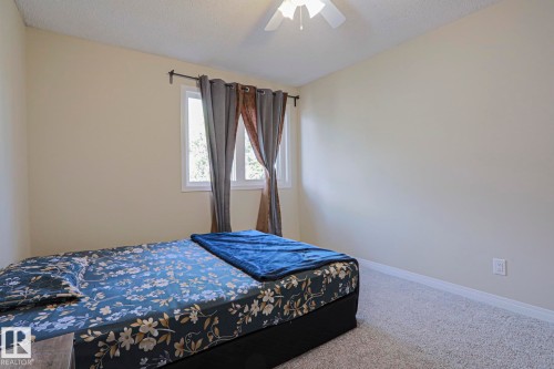 Neutral-toned walls, light-colored carpet, a ceiling fan, and a window with white trim - 319 Telford Court, Leduc, AB 