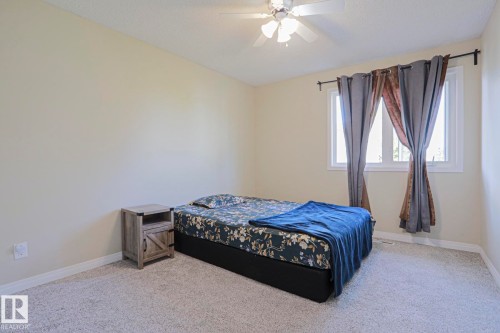 Neutral wall color, ceiling-mounted light fixture with fan, large window with white frame, and wall-to-wall carpeting - 319 Telford Court, Leduc, AB 