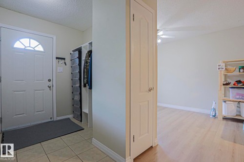 Entryway featuring a white paneled door with an arched transom window, ceramic tile flooring, and a built-in storage unit - 319 Telford Court, Leduc, AB 