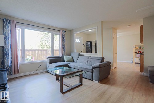 Expansive living area featuring light wood-finish flooring, a large window, and light-toned wall finishes - 319 Telford Court, Leduc, AB 