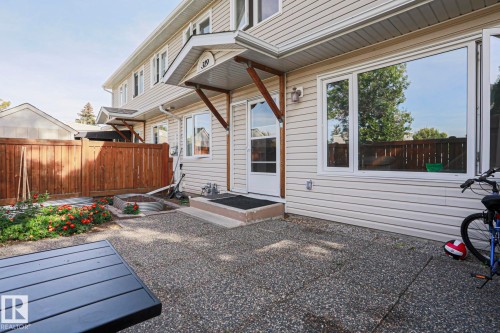 Rear patio with exposed aggregate paving, a wood privacy fence, and a garden bed - 319 Telford Court, Leduc, AB 