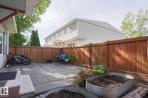 Fenced backyard featuring a paver patio and raised garden beds - 319 Telford Court, Leduc, AB 