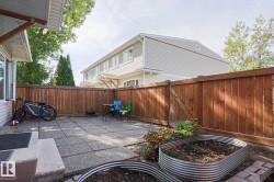 Fenced backyard featuring a paver patio and raised garden beds - 