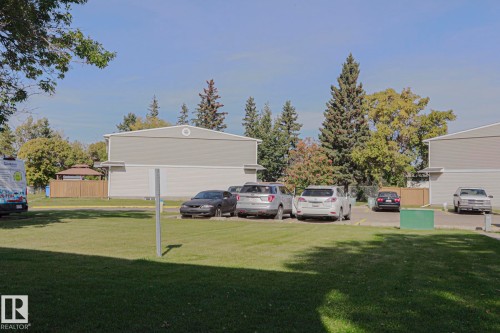Expansive green space featuring mature trees and a fenced gazebo structure - 319 Telford Court, Leduc, AB 
