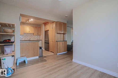 Kitchen featuring wood cabinetry, stainless steel refrigerator, and tiled backsplash - 319 Telford Court, Leduc, AB 