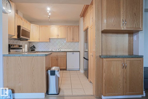 Kitchen featuring light wood-finish cabinetry, tile flooring, diagonal tile backsplash, and track lighting - 319 Telford Court, Leduc, AB 