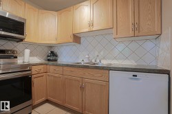 Light wood cabinetry, stainless steel range, built-in microwave, white tile backsplash, and a double basin sink - 