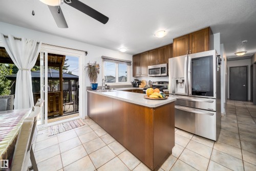 Kitchen featuring tile flooring, wood cabinetry, stainless steel appliances, and a light-toned countertop - 10245 160 Street Nw, Edmonton, AB 