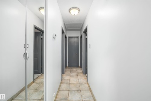 Hallway featuring tile flooring, flush mount lighting, and neutral wall tones - 10245 160 Street Nw, Edmonton, AB 