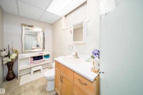 Wood-finish vanity with a white countertop and integrated sink - 10245 160 Street Nw, Edmonton, AB 