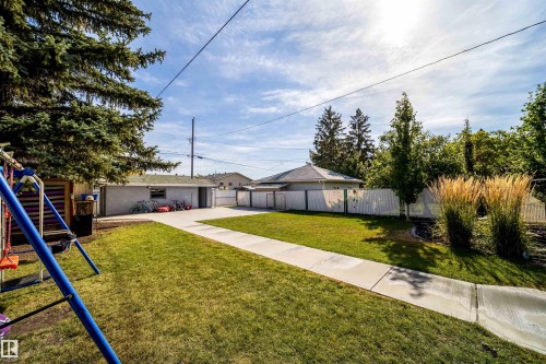 Expansive backyard with a manicured lawn, concrete pathway, and mature landscaping - 10245 160 Street Nw, Edmonton, AB 