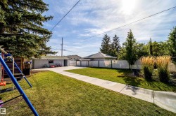 Expansive backyard with a manicured lawn, concrete pathway, and mature landscaping - 