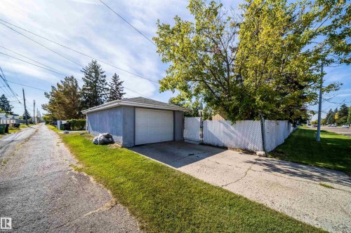 Detached garage featuring a white overhead door, concrete driveway, and white chain-link fencing - 10245 160 Street Nw, Edmonton, AB 