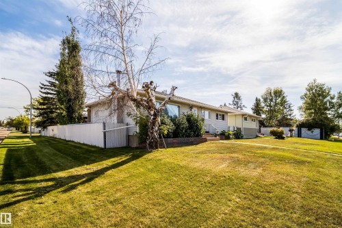 Expansive front yard with a white picket fence, mature trees, and established landscaping - 10245 160 Street Nw, Edmonton, AB 