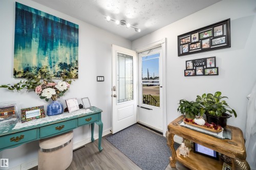 Entryway featuring wood-finish flooring, a white paneled door with decorative glass inserts, and track lighting - 10245 160 Street Nw, Edmonton, AB 