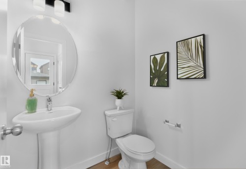 Pedestal sink with chrome faucet, oval mirror, and overhead vanity lighting - 121 Chelles Wynd, St. Albert, AB 